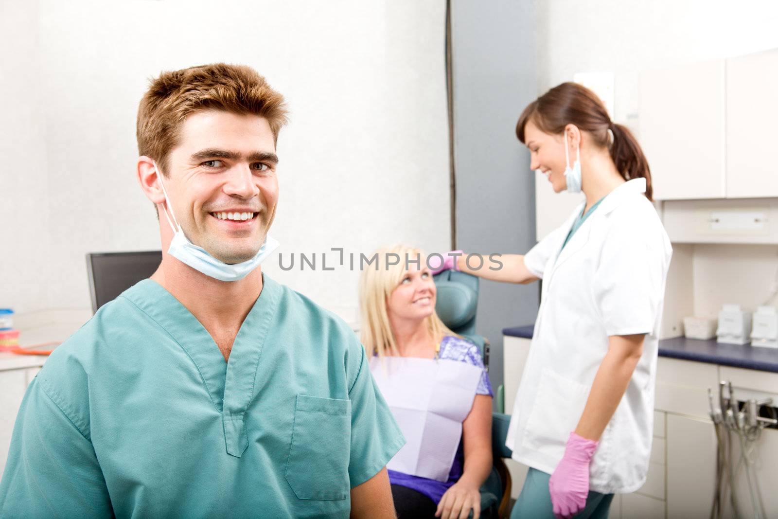 A happy smiling dentist at a clinic with an assistant and patient