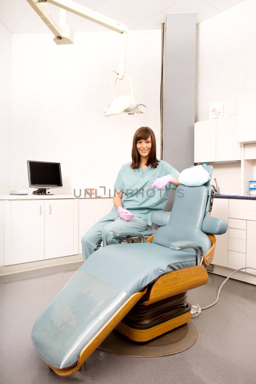 A dental hygienist sitting at a dental chair in a clinic