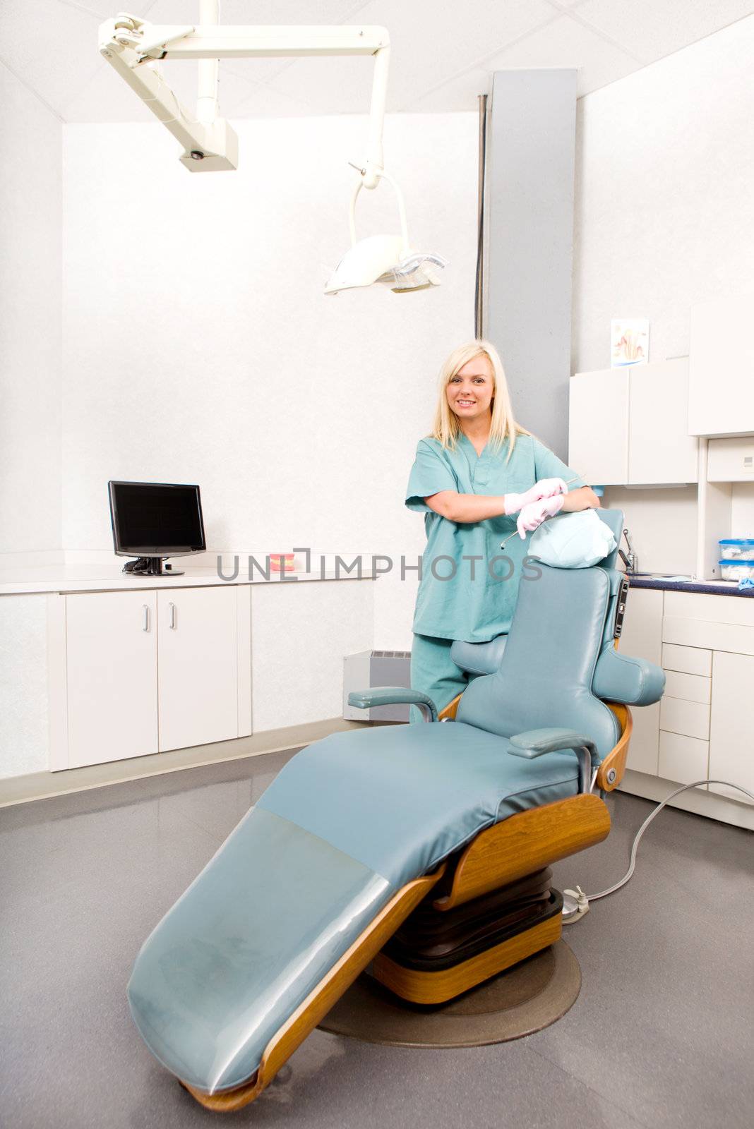A happy assistant / hygienist standing by a dental chair