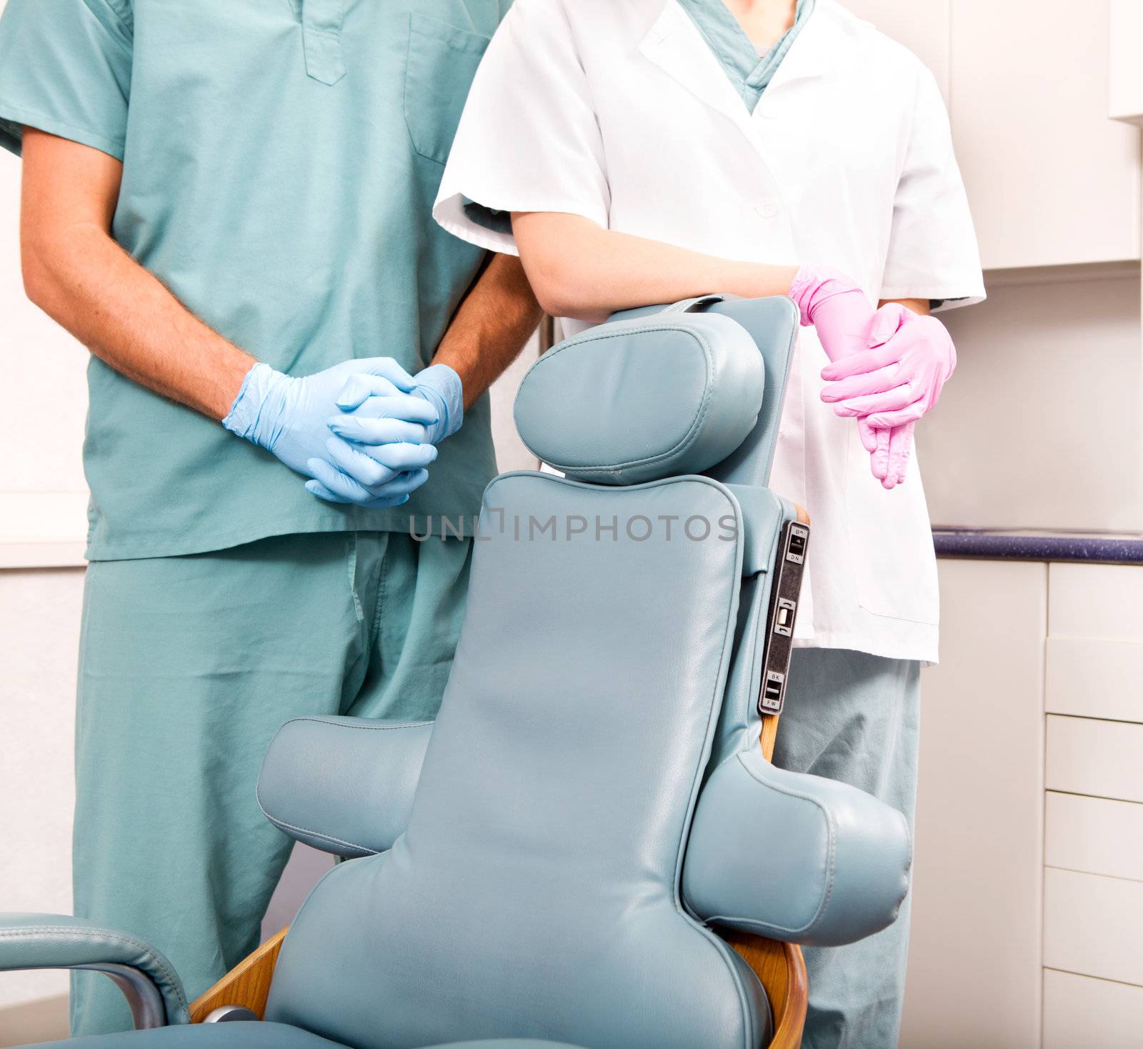A dentist and assistant at a dental clinic standing by a dental chair