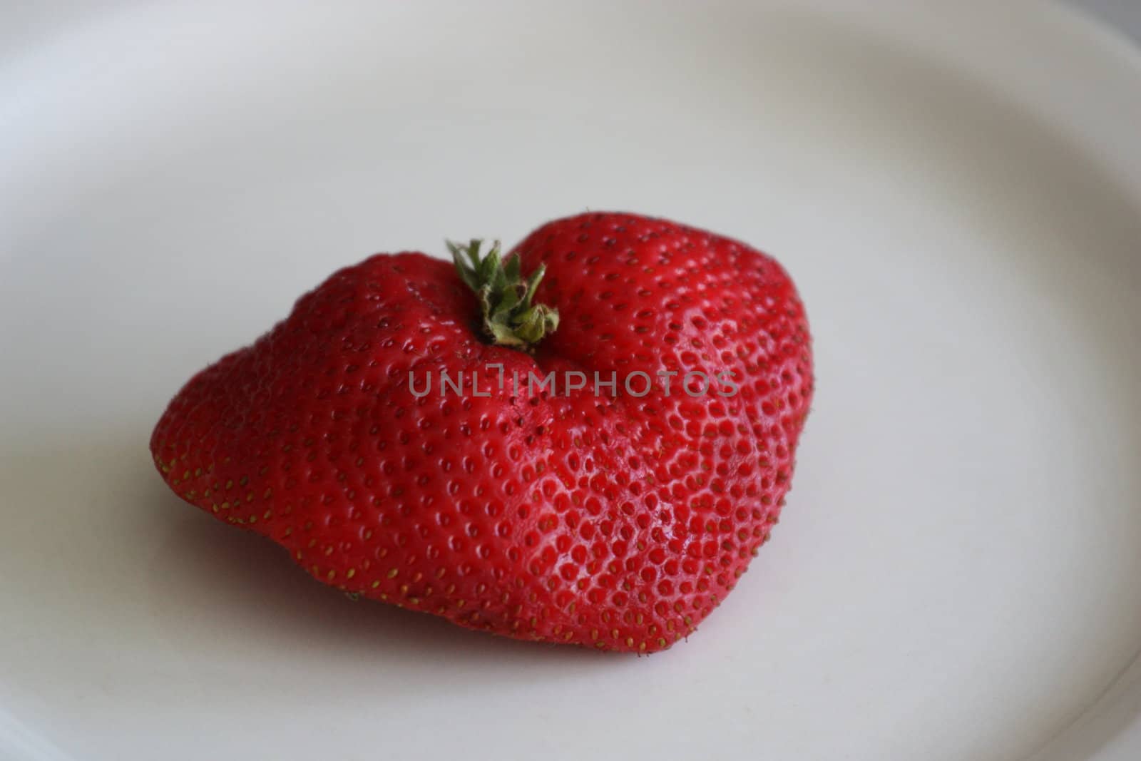 Close up of a strawberry on a plate.
