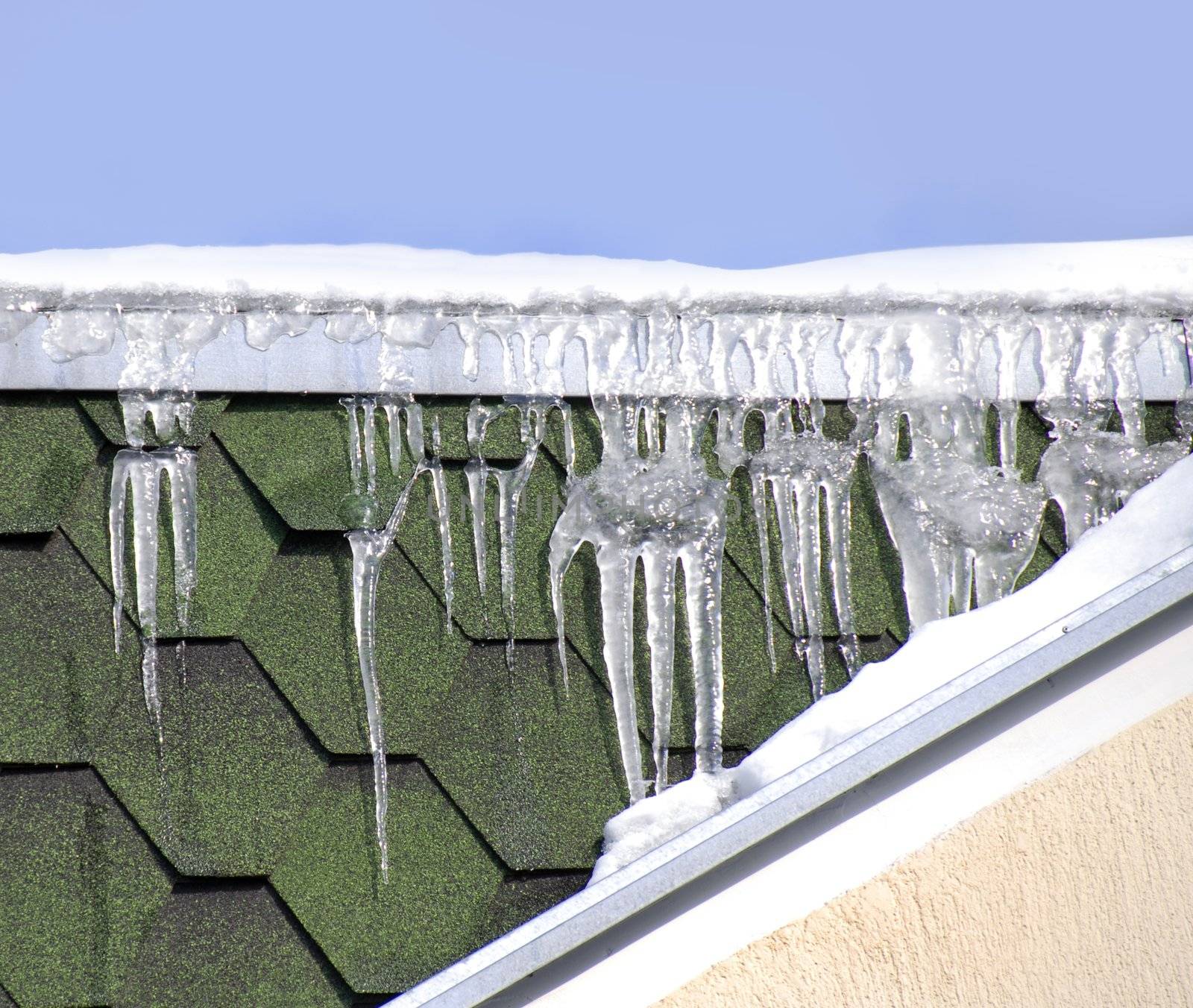 ice on green winter roof over blue sky