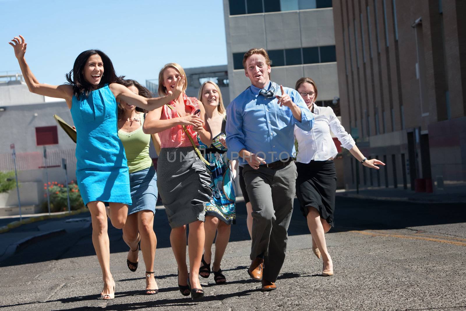 Happy men and women running down the street.