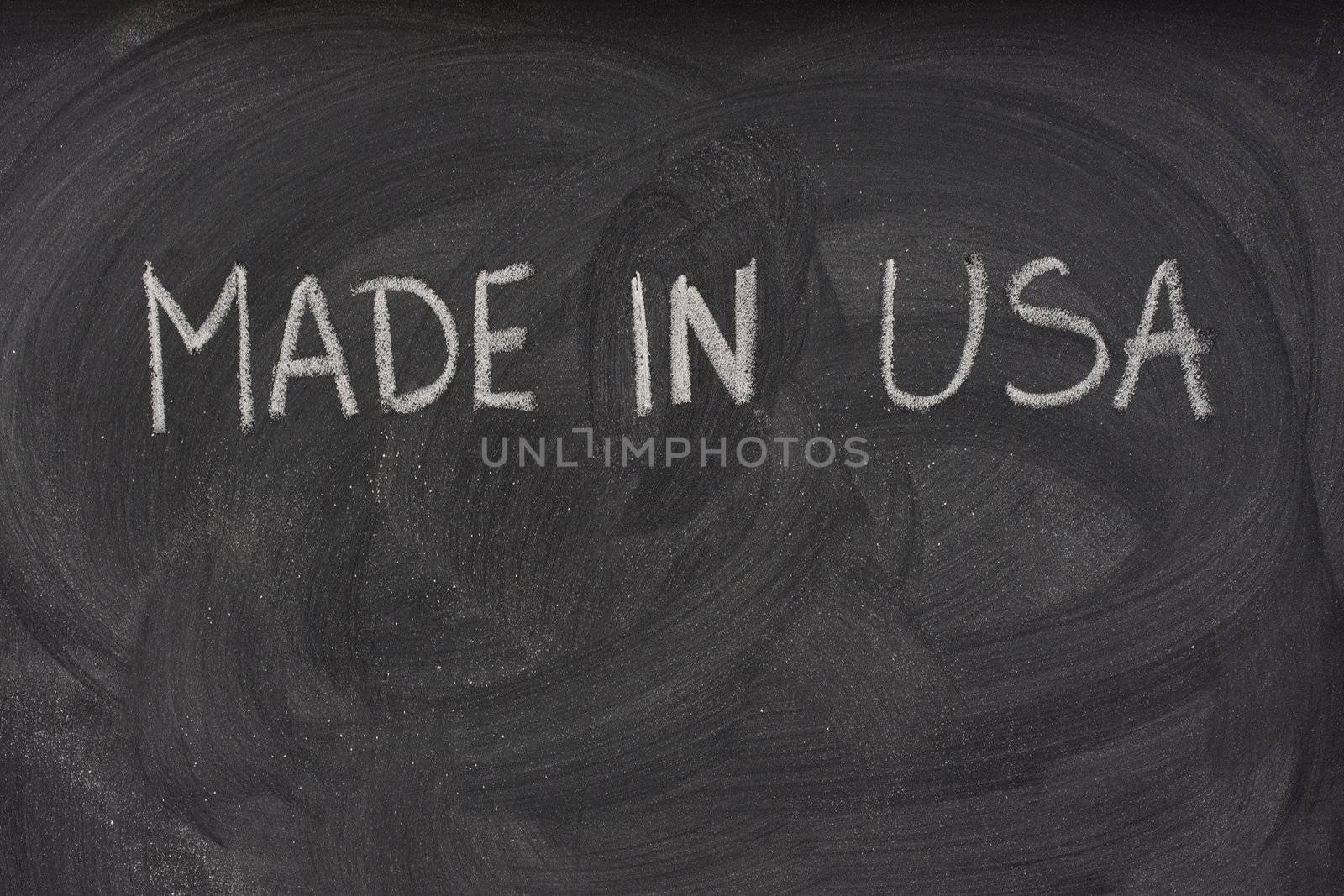 made in USA phrase handwritten with white chalk  on a blackboard with eraser smudges and copy space below