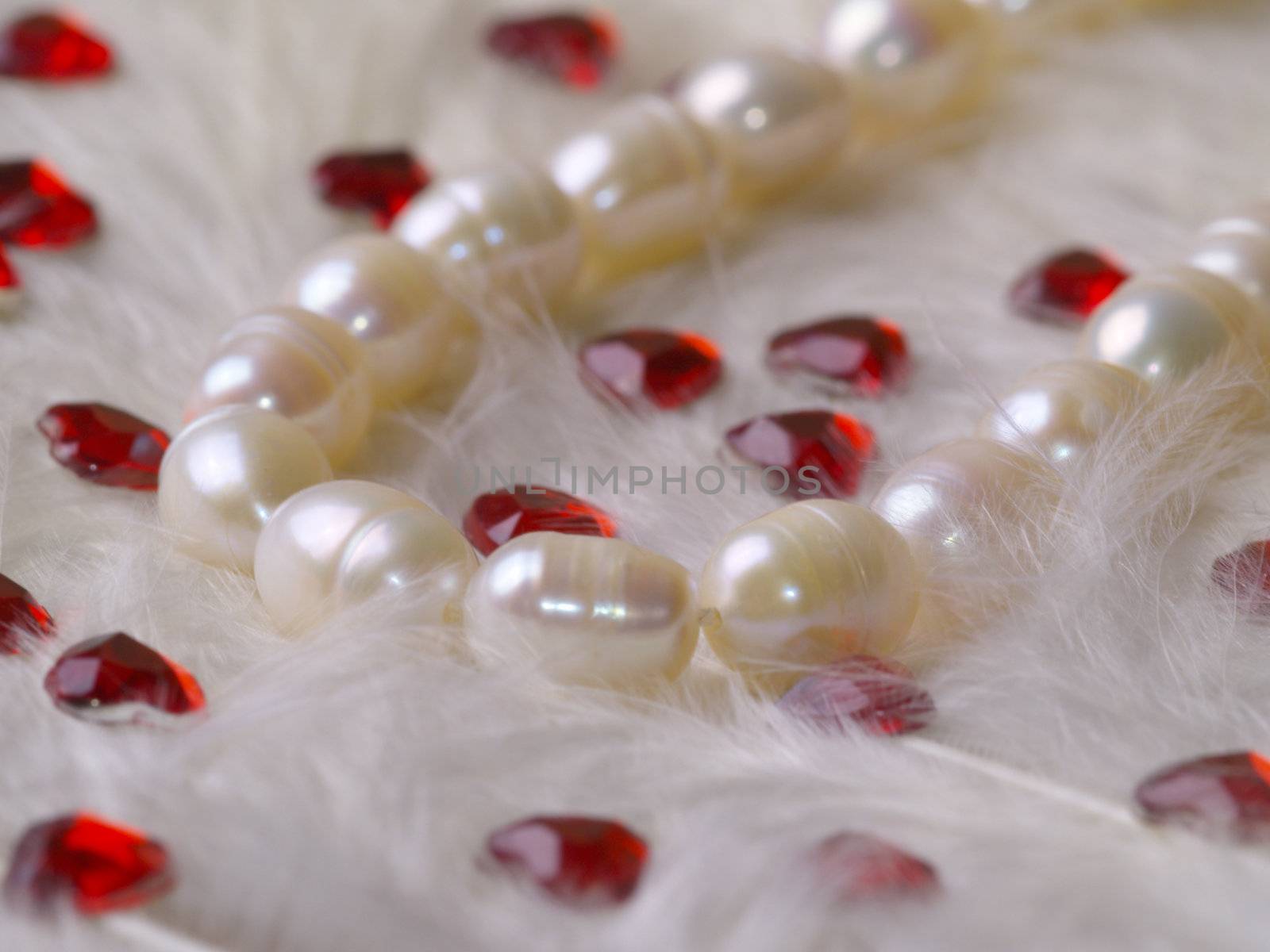 detail of pearl necklace on white feathers with strass hearts