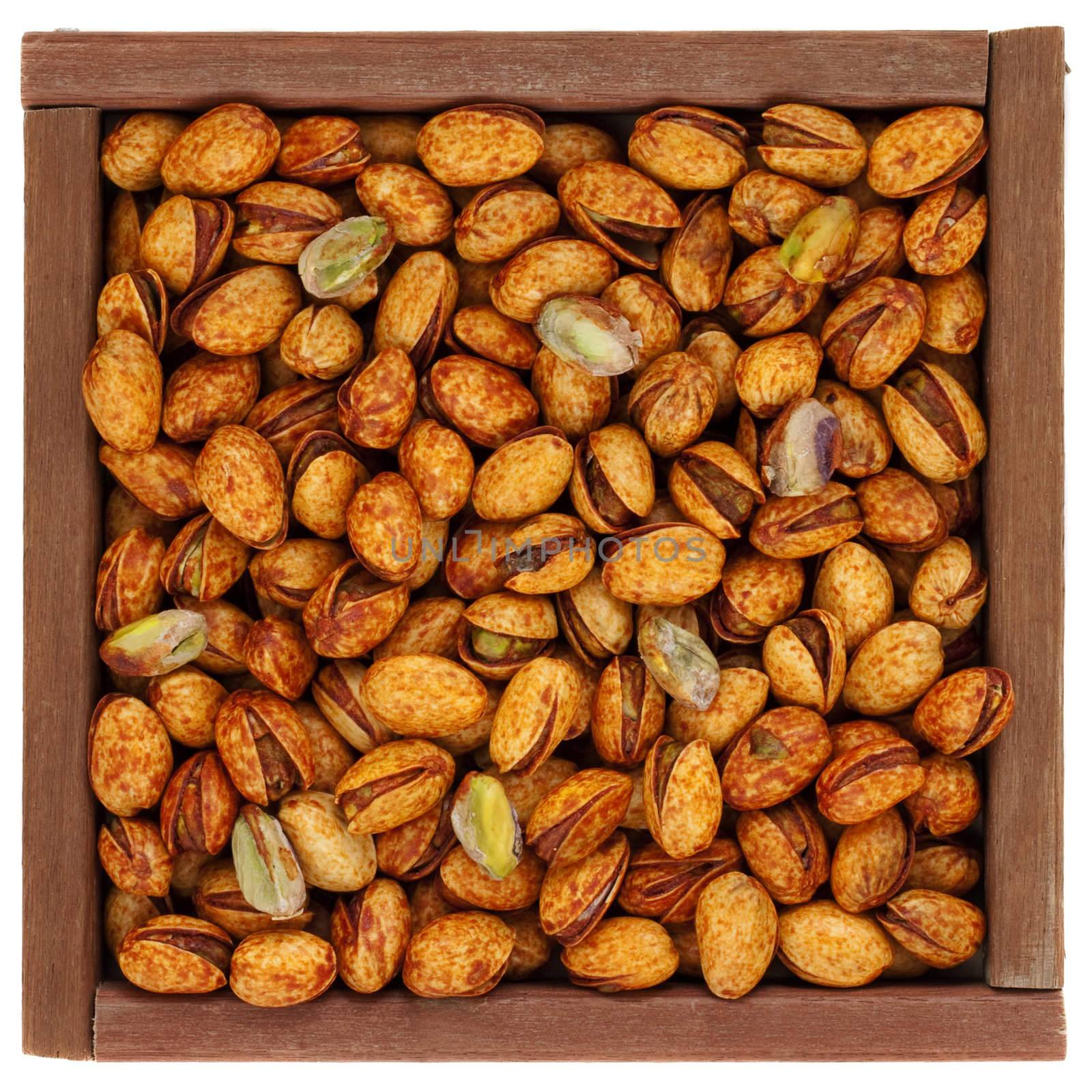 roasted chili lemon pistachio nuts with shells in a rustic, square, wooden box or frame, isolated on white