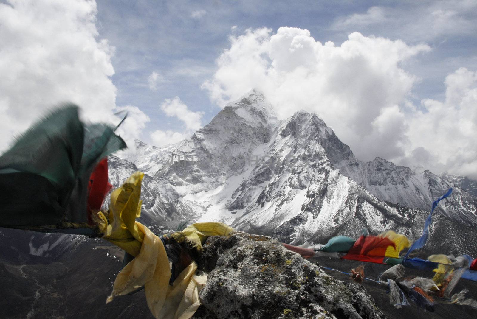 The North face of _Ama Dablam_  (6812 m) in the Himalayan Mountain Range as seen from the peak of _Pokalde Ri_  (5330 m) on the trek from Lukla to Mt. Everest Base Camp. Tibetian Buddist prayer flags flap in the wind in the foreground
