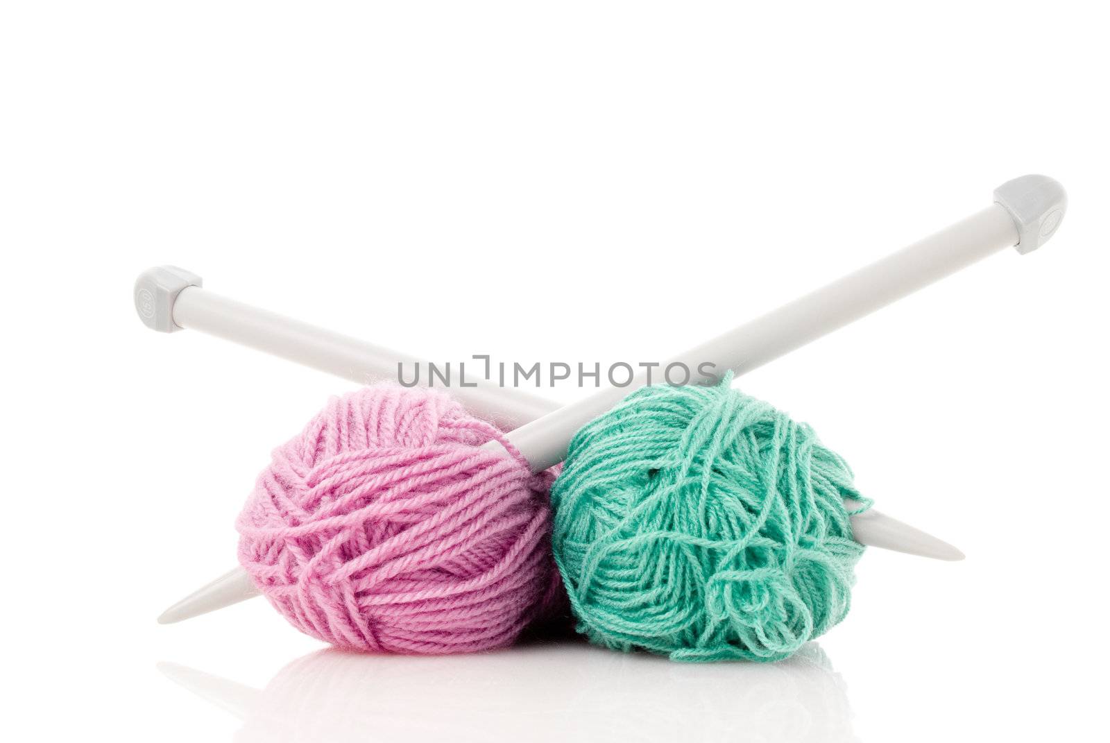 Balls of green and pink  knitting wool or yarn, with silver knitting needles.