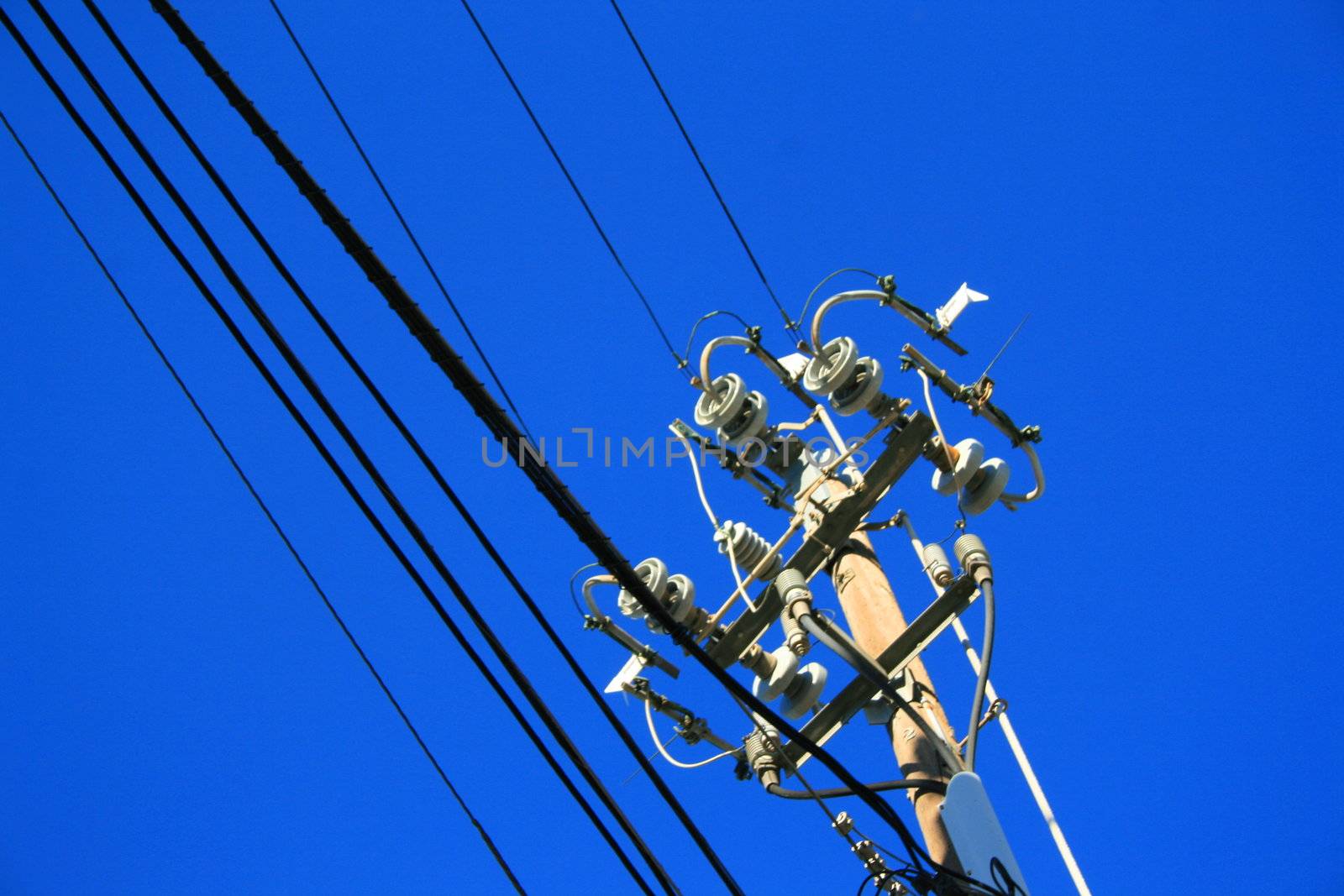 Close up of an electricity pole over blue sky.
