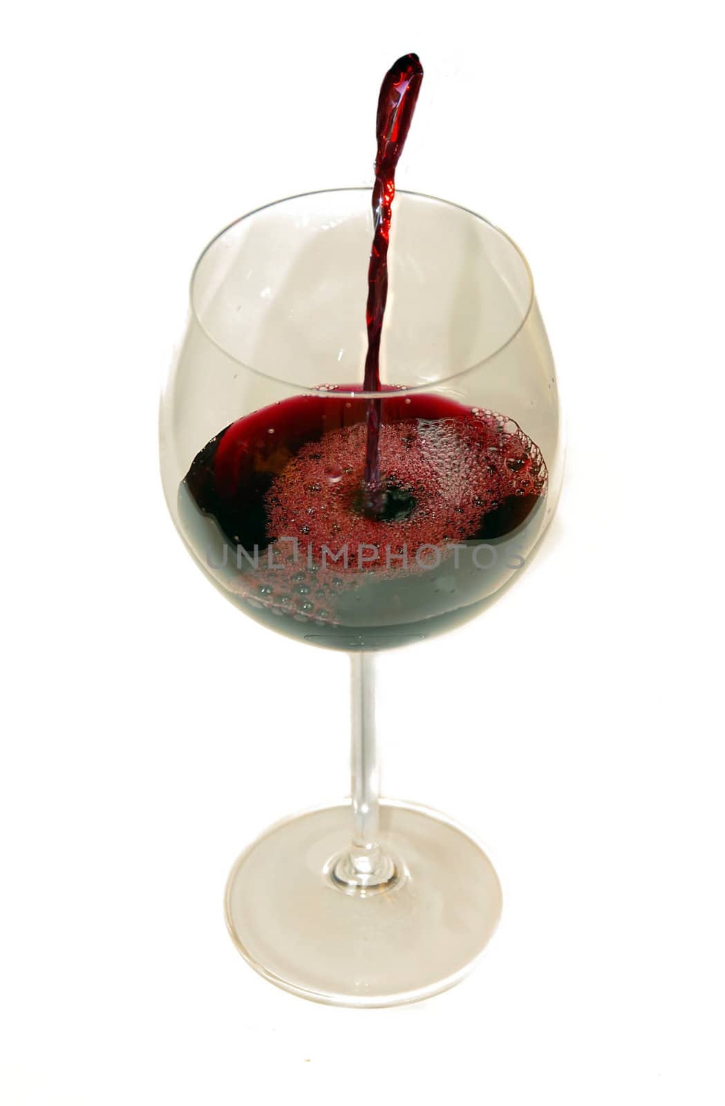Pouring red wine into wineglass from green bottle