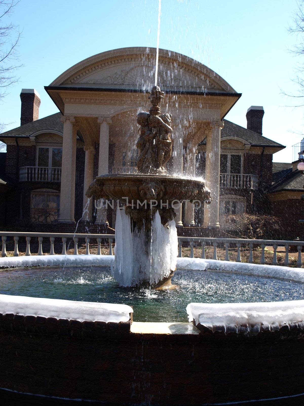 A frozen fountain in front of a large house