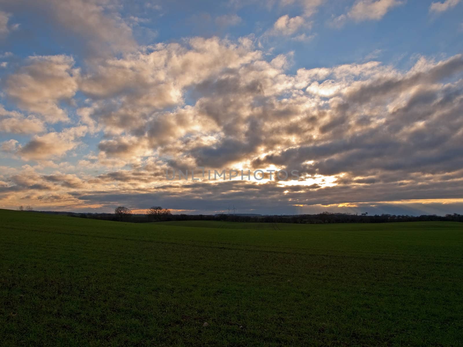 Dramatic sunset with cloudscape over a green field background