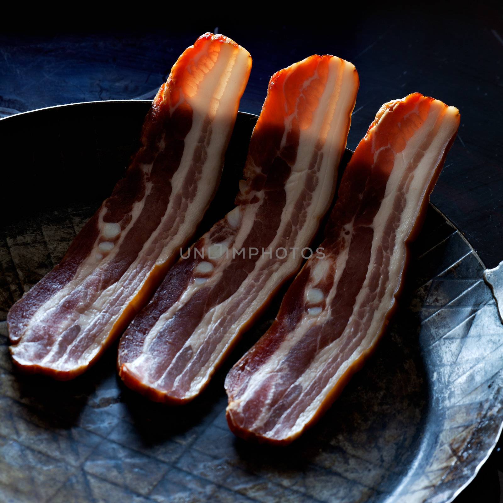 three stripes of bacon in a pan