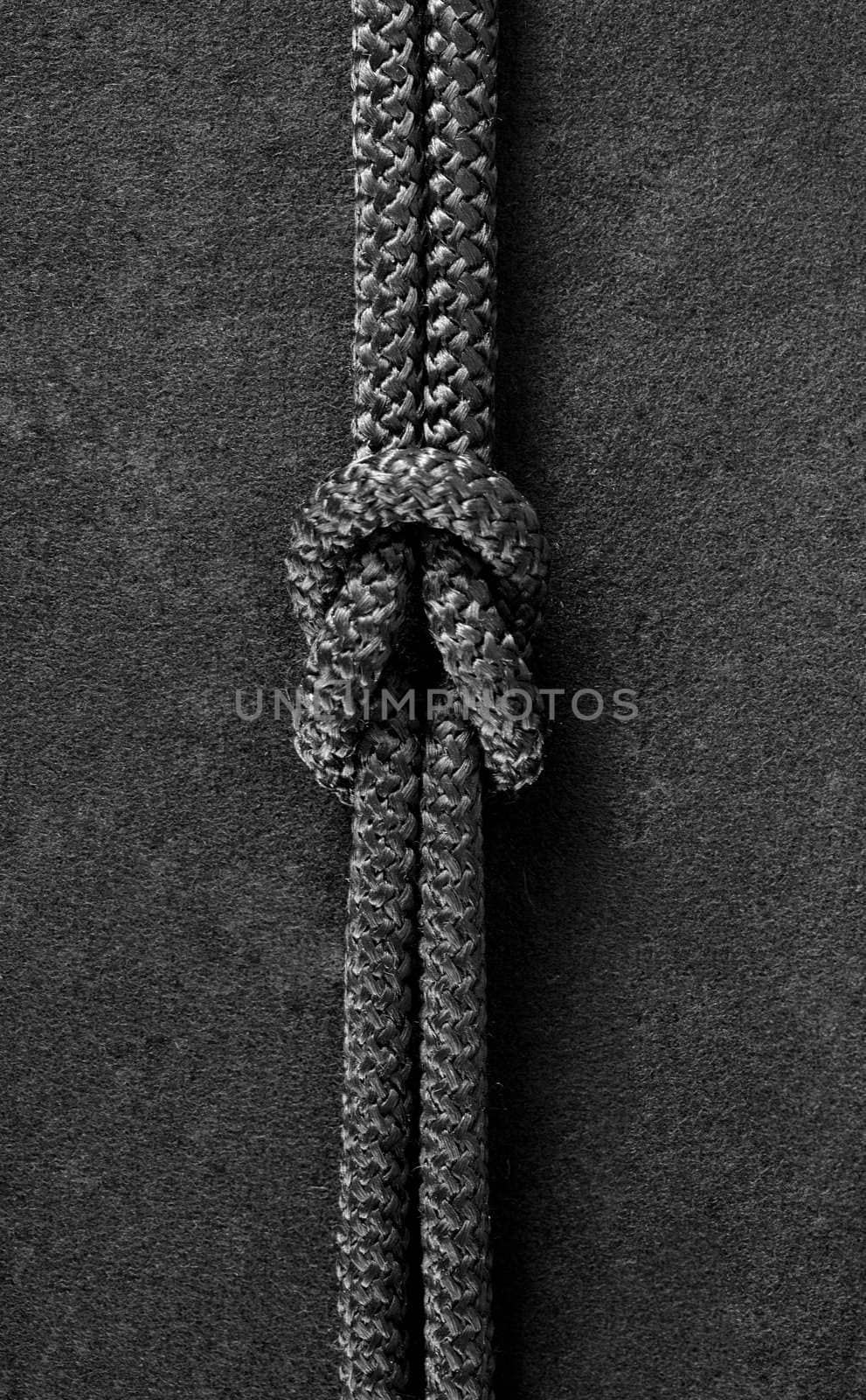 Bend knot on black cord on the black fabric background
