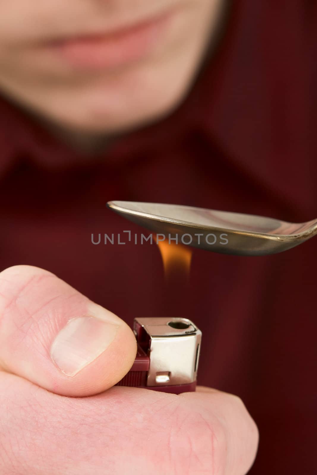 Young man cooking drug in tea-spoon with the help of lighter