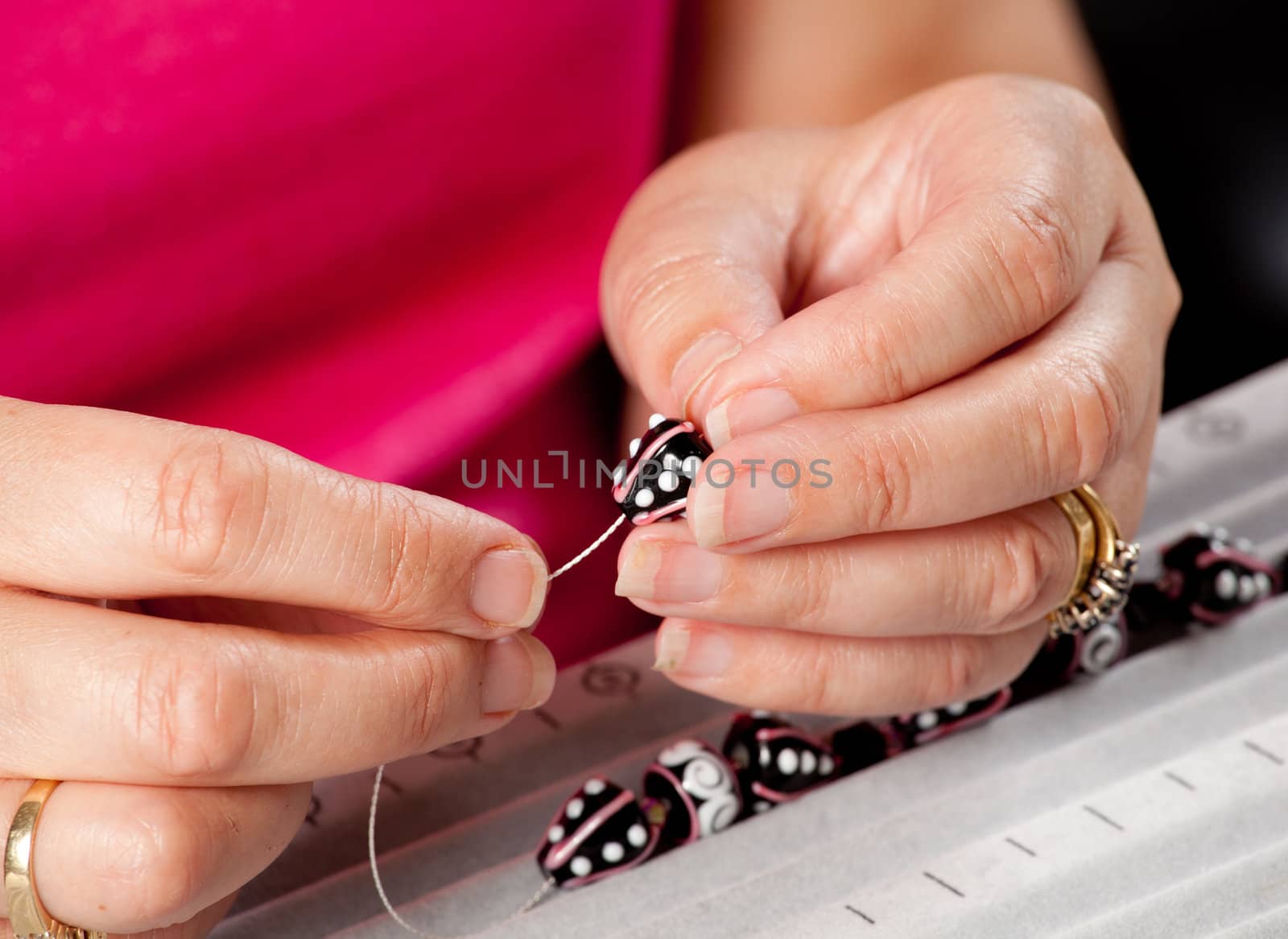 Close up of threading beads onto wire to make artistic bead necklace or bracelet