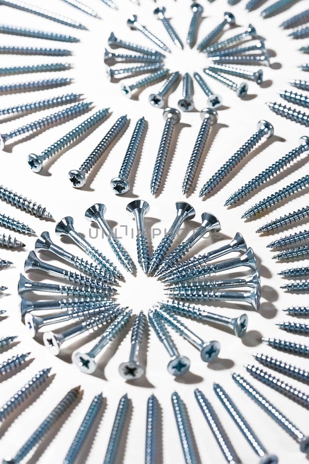 Picture made of screws different sizes on a white textile, metal and cloth.

