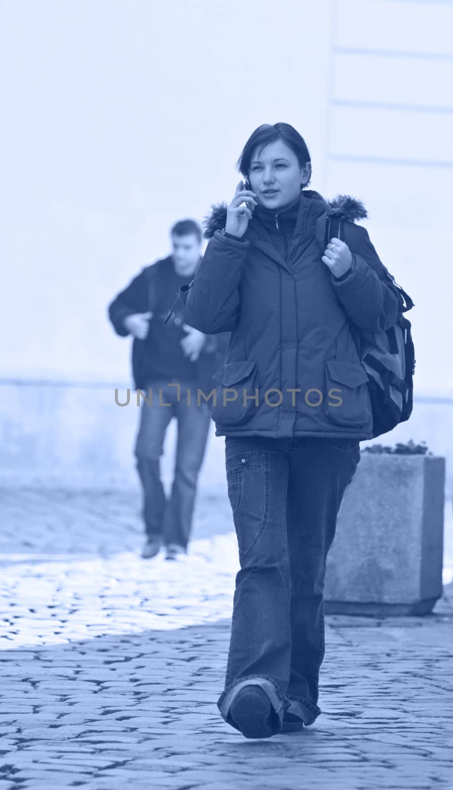 Redheaded girl student at the phone while is walking on a paved street-blue tones.