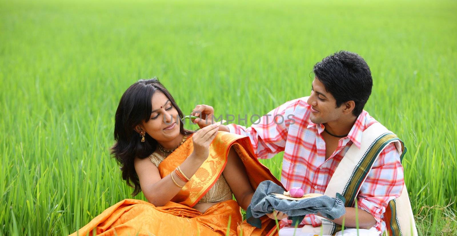 young couple sitting in the paddy field by GAMUTSTOCKIMAGES