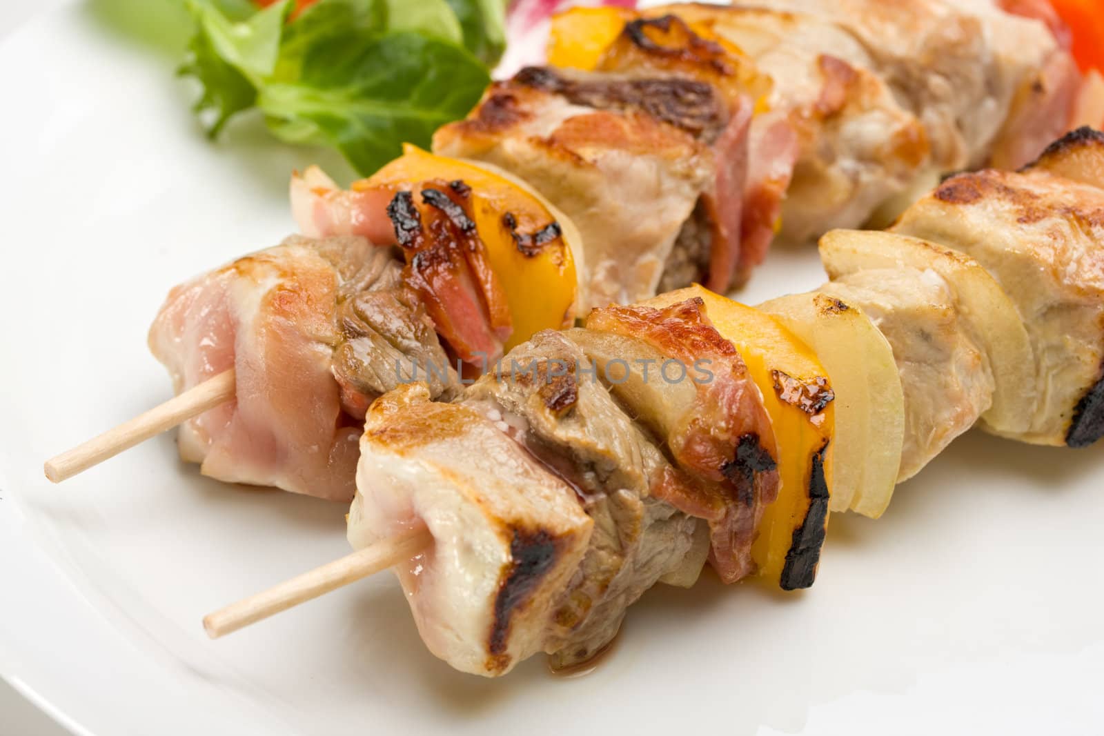 shashlik on a plate with a tomato and salad leaf