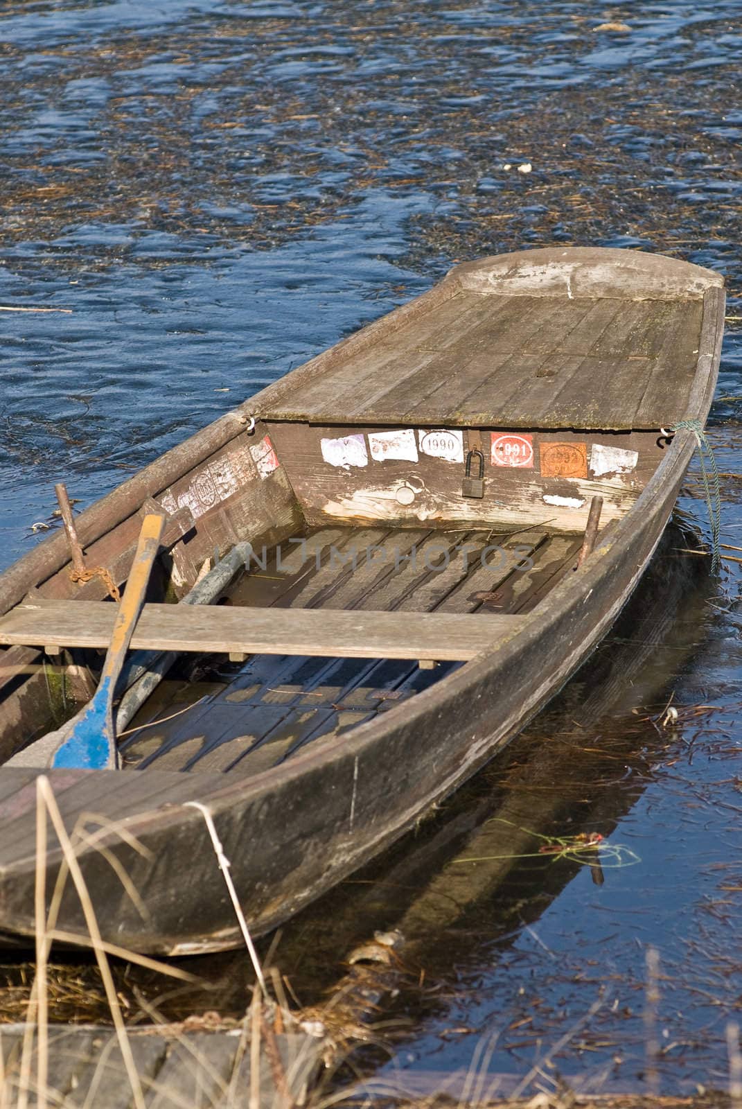 a boat which is frozen in the lake with a meditative beautiful mood in a romantic winter landscape