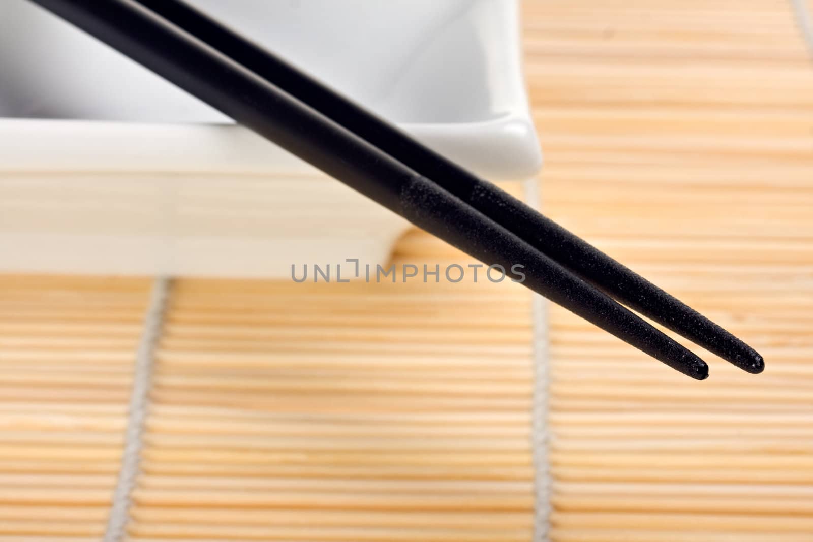 pair of chopsticks on a bamboo mat by bernjuer