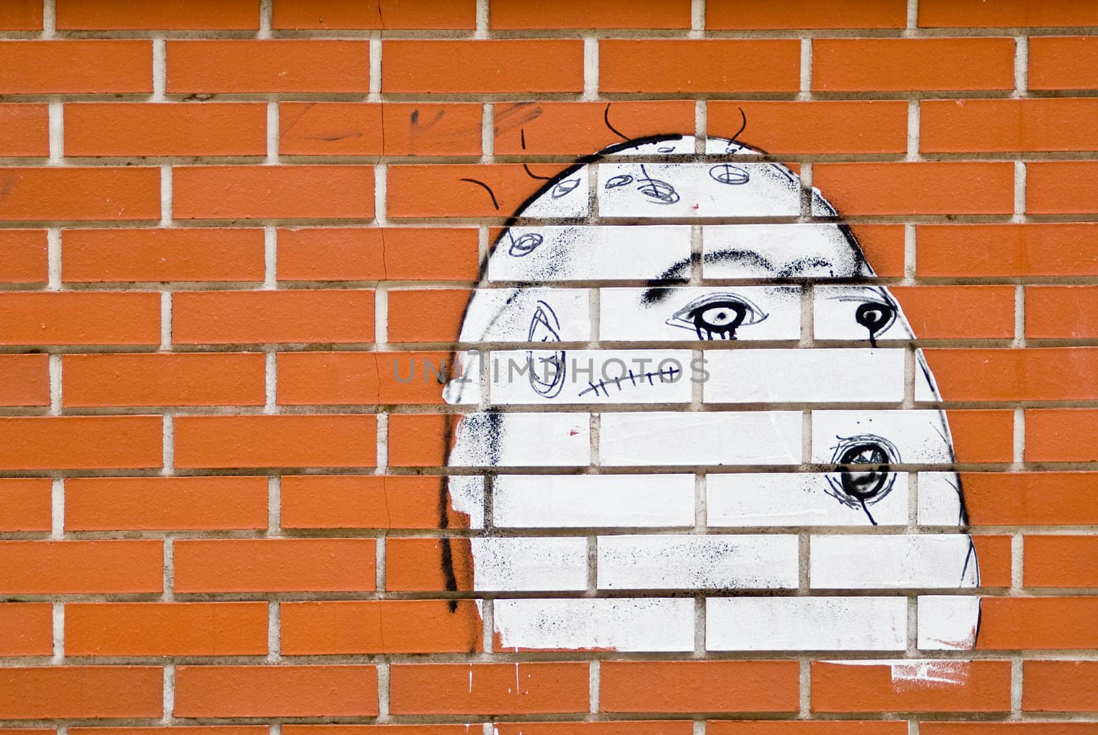 a brickwall with a graffiti showing an ugly white face