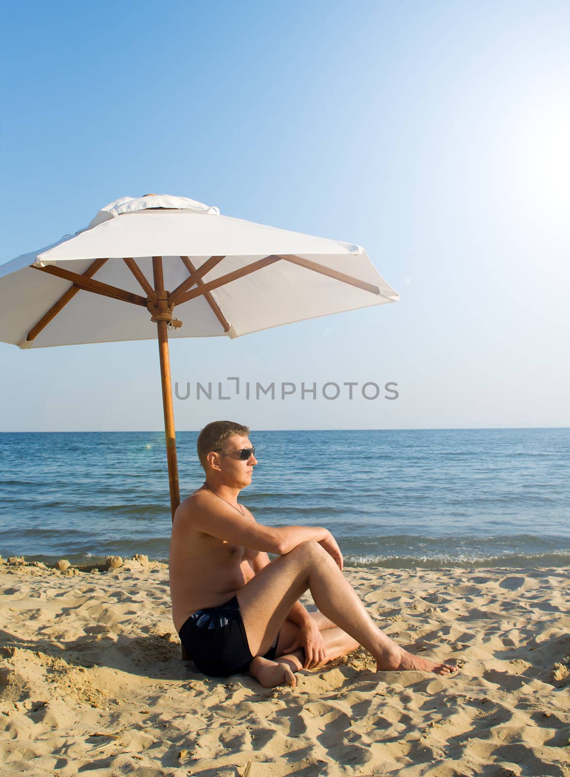 The man under a solar umbrella on a beach