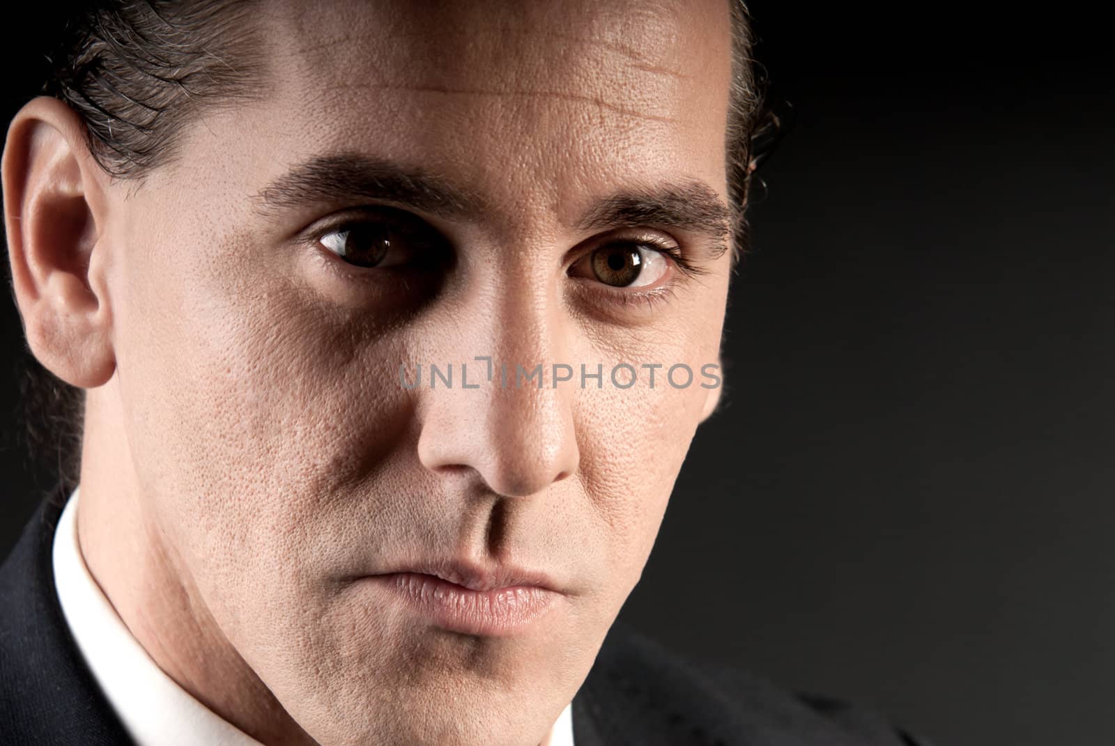 Adult businessman closeup portrait on dark background. by dgmata