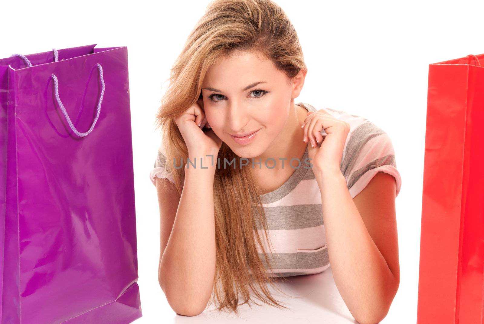 Young woman with shopping bags lying on floor on white background by dgmata