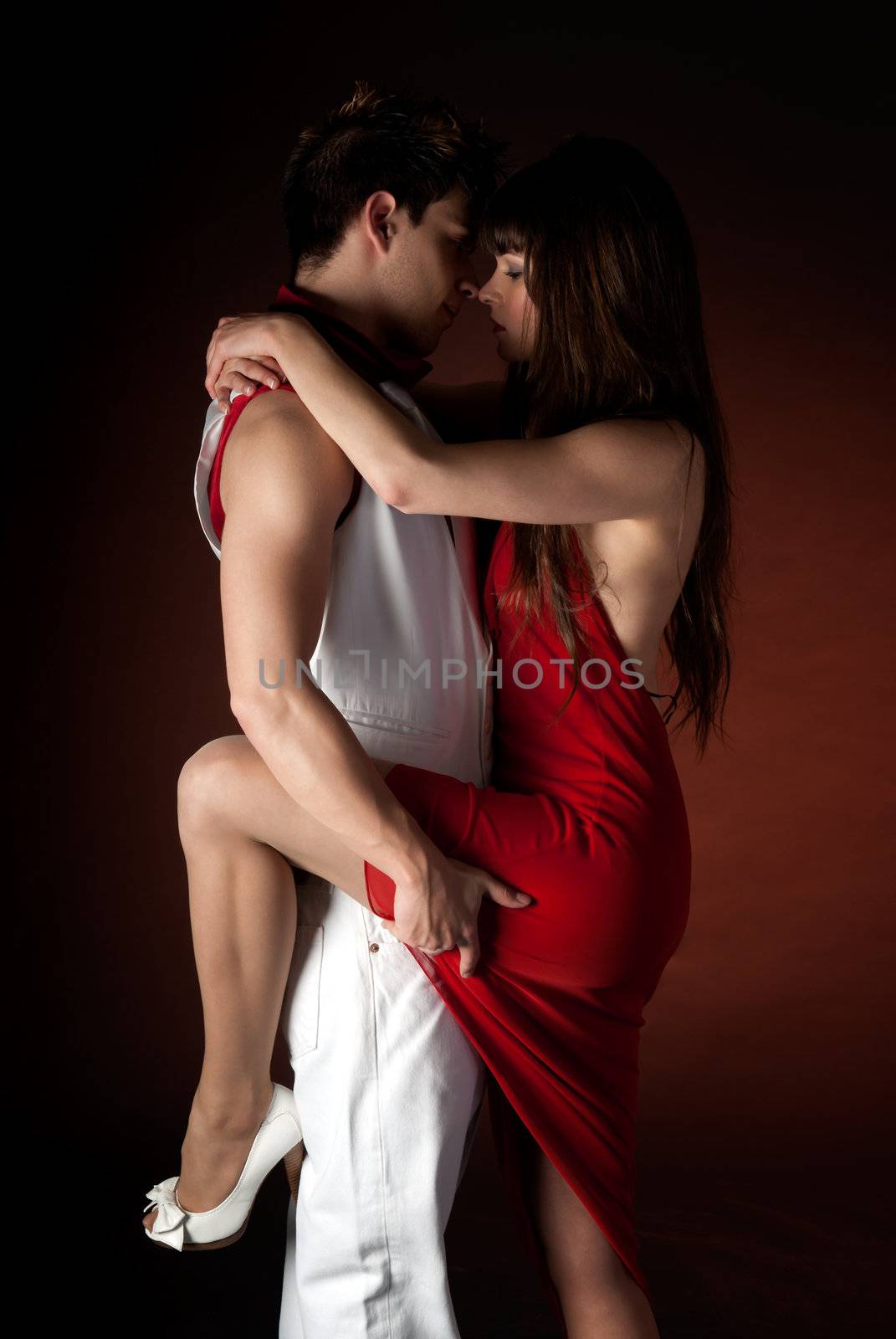 Young couple dancing embrace passion romance on dark red light background. by dgmata