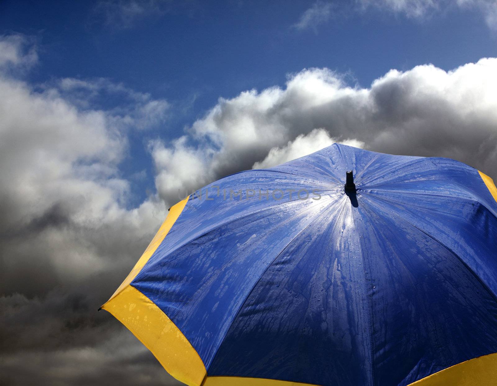 Blue - yellow beach umbrella on a background clouds