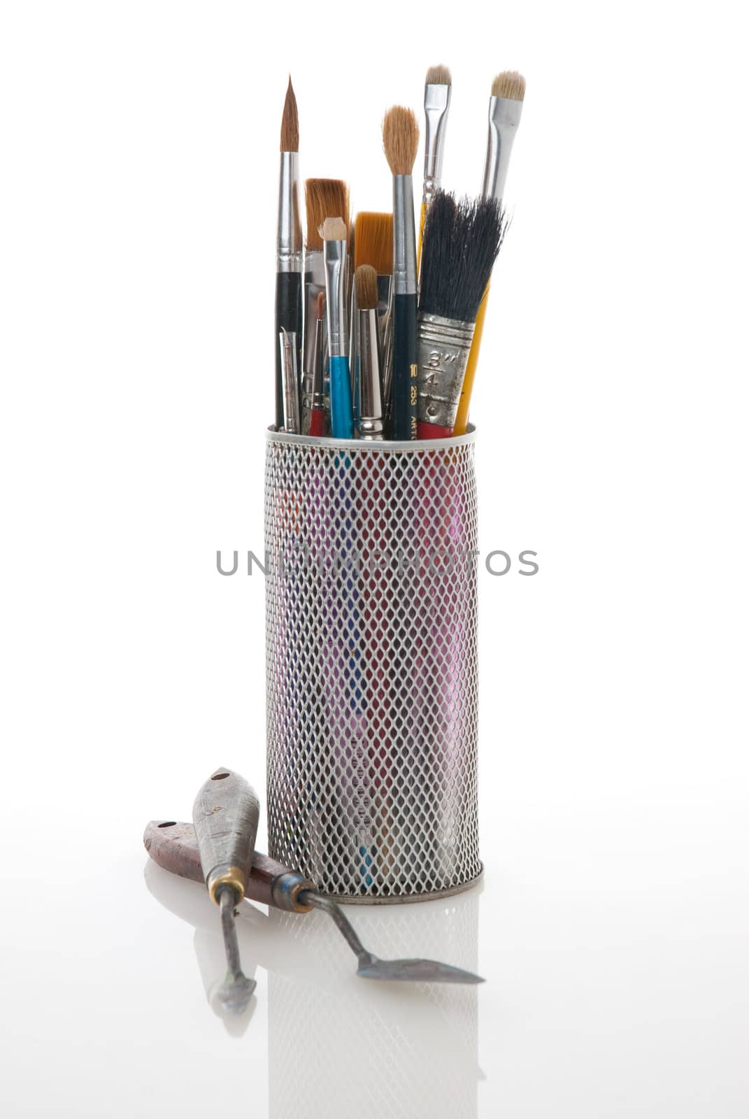 Paintbrushes in a metal mesh holder on white background.