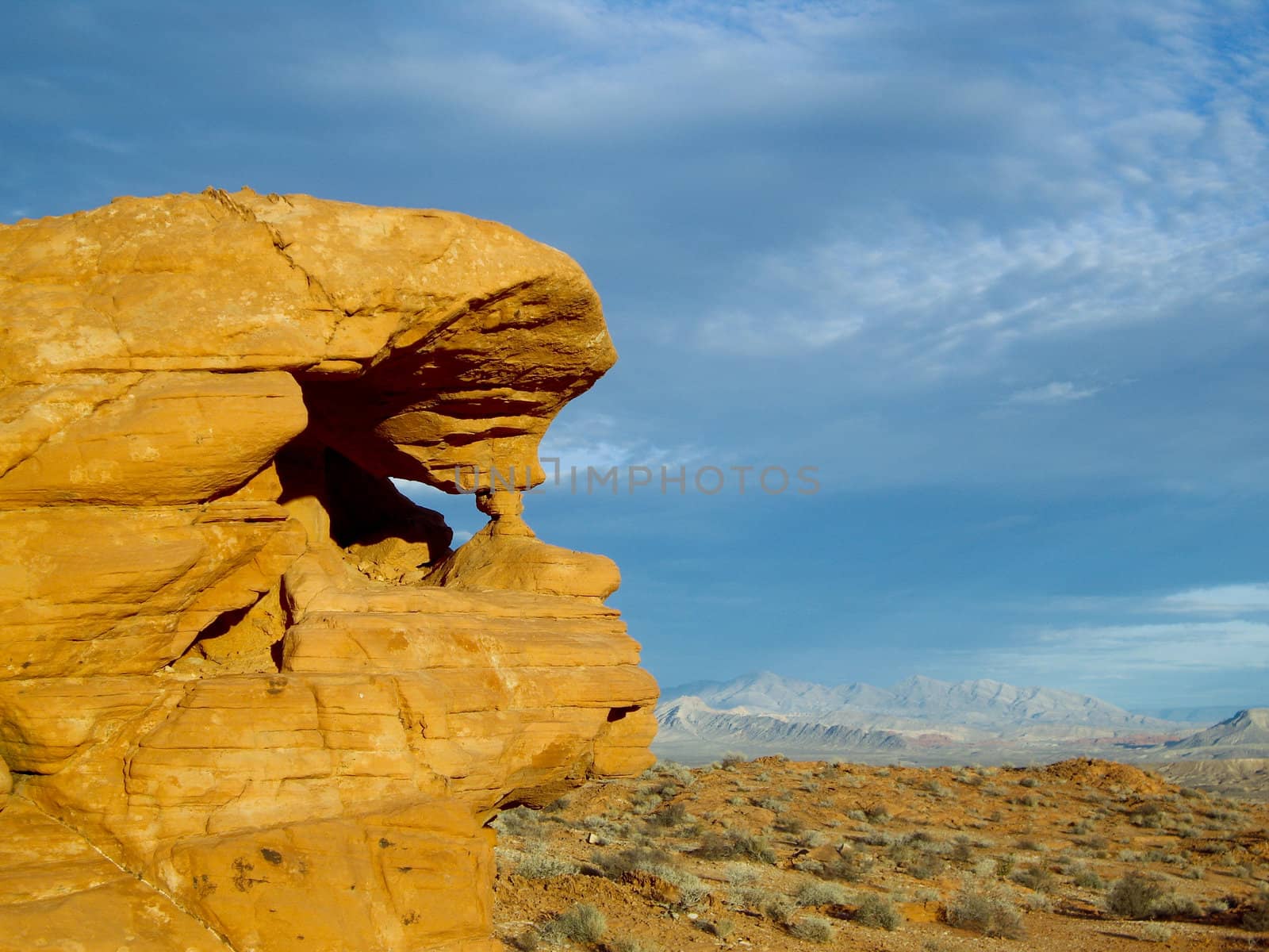 Sandstone formation stands guard over soft desert landscape