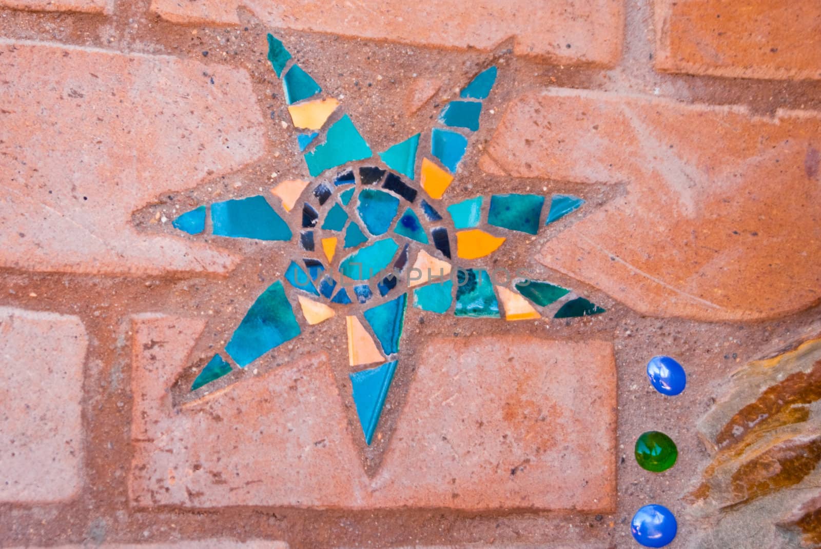 Star mosaic in blues with three color tiles on brick.
