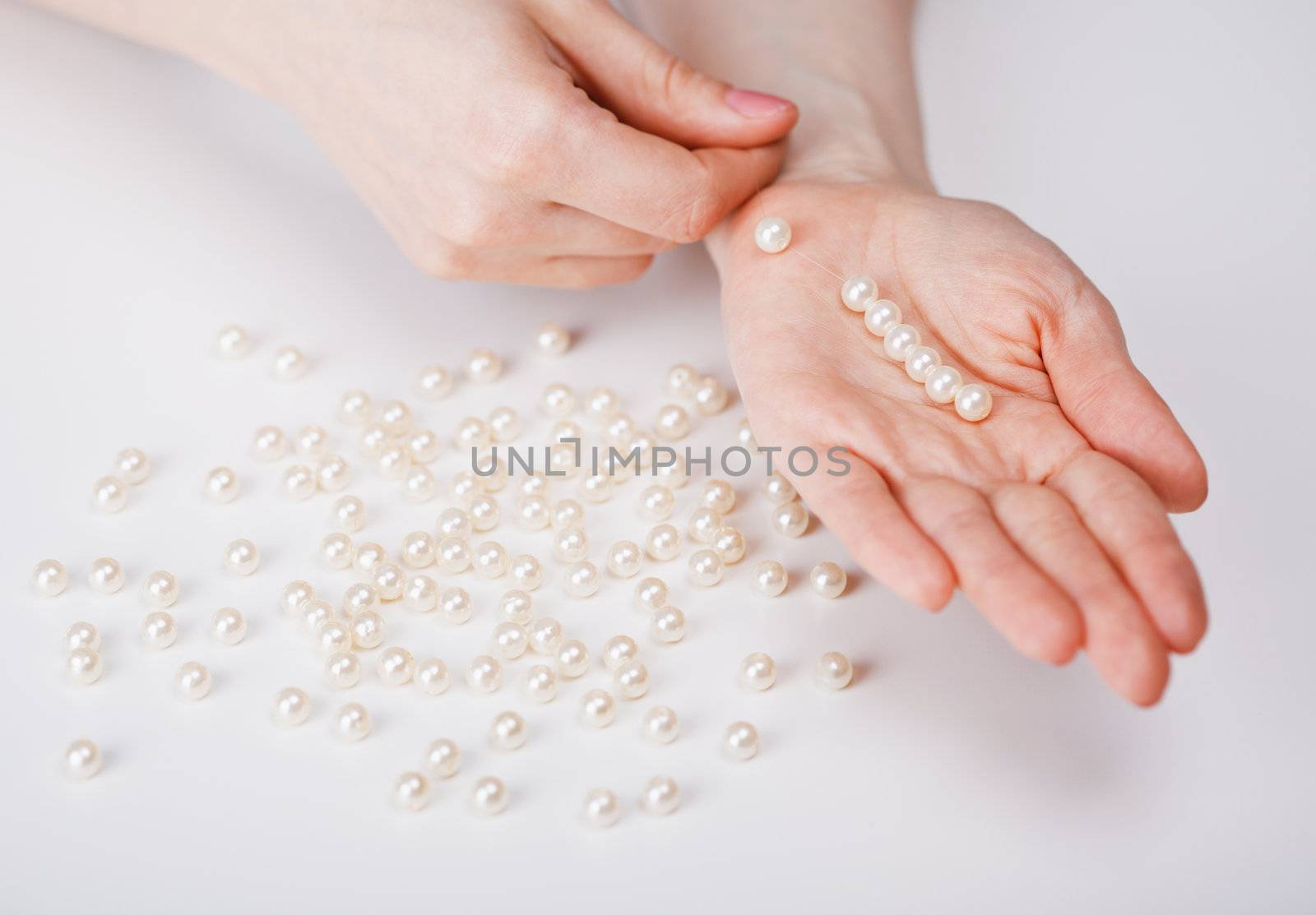 Female hands a collecting beads from large pearls
