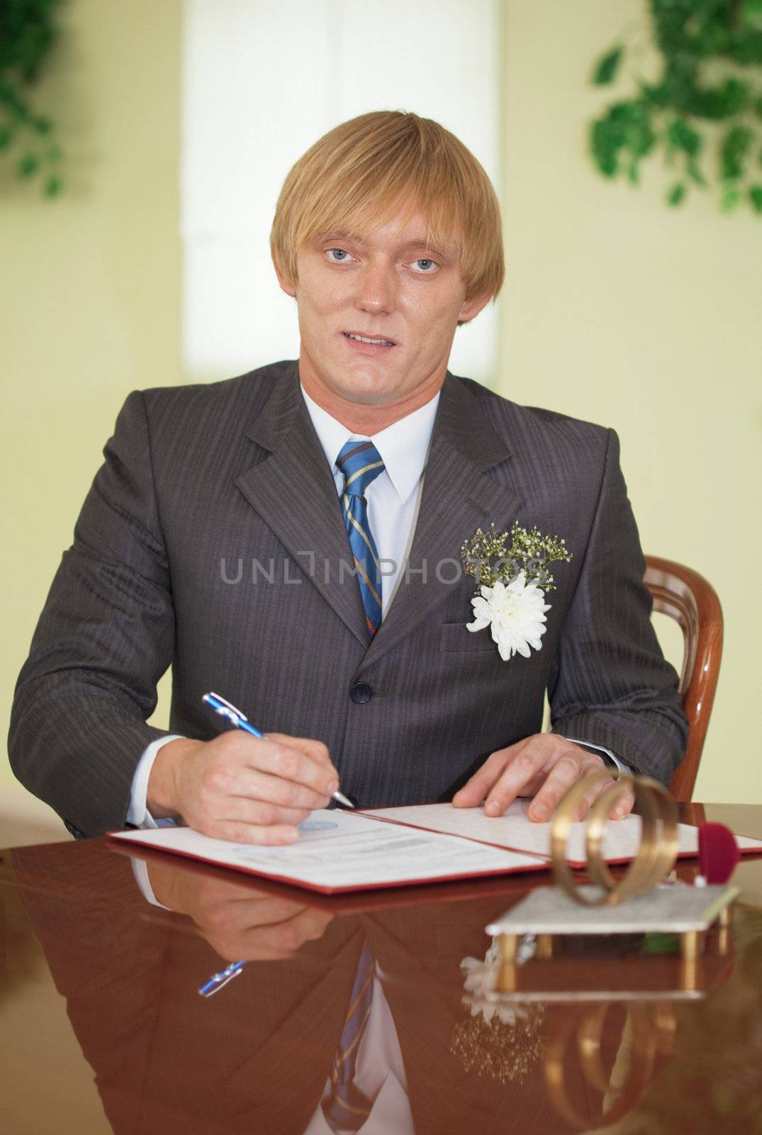 The groom puts his signature on the registration document