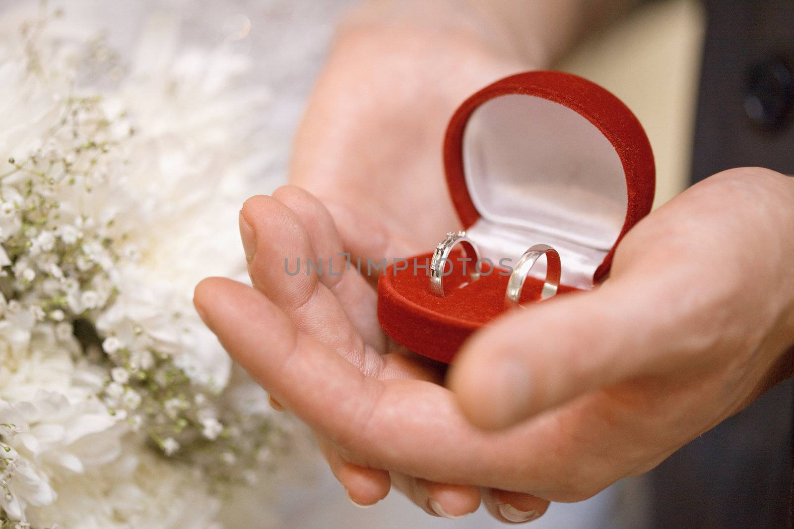 Hands of the groom and the bride hold a casket with rings close up