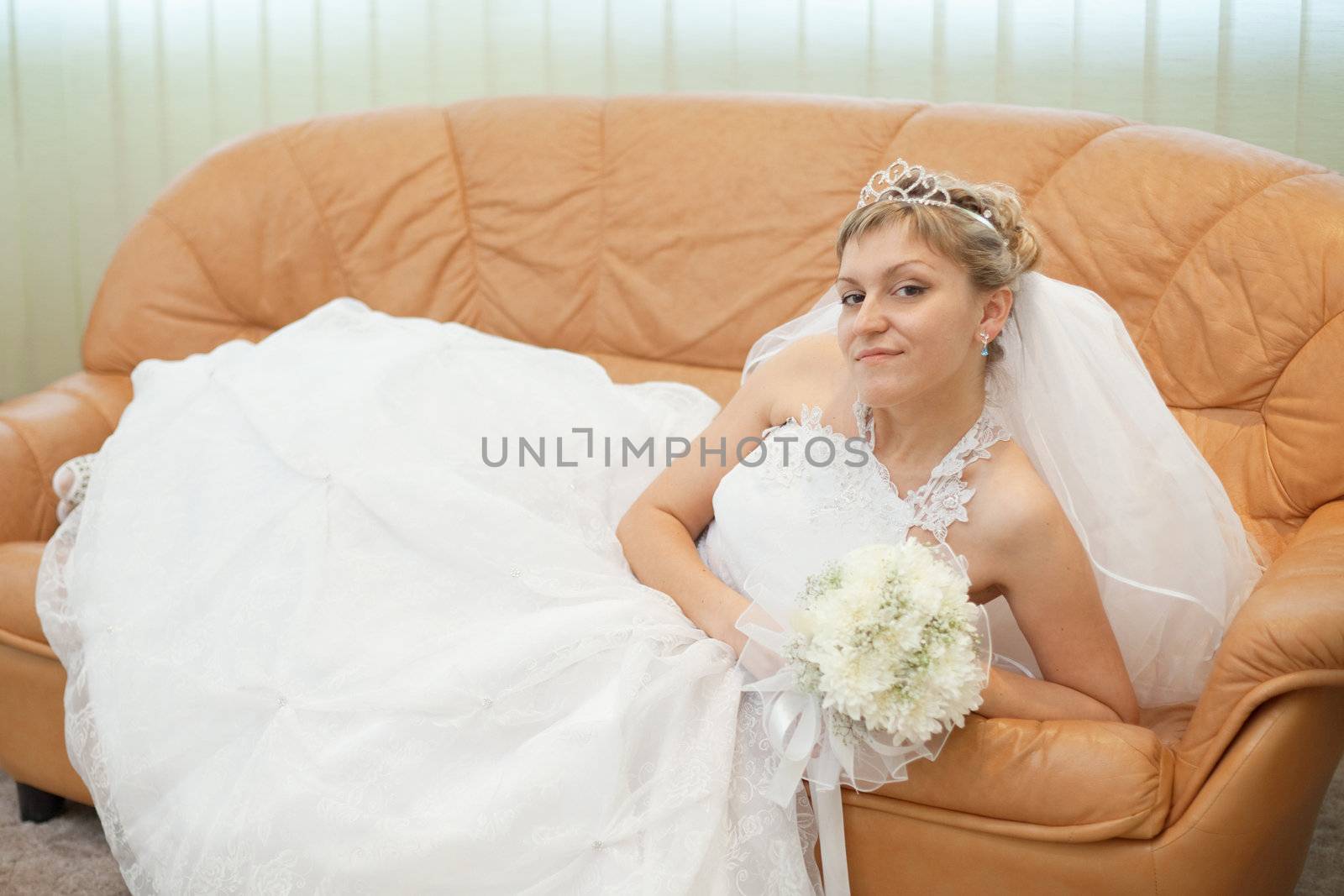 The bride comfortably lies on the big leather sofa