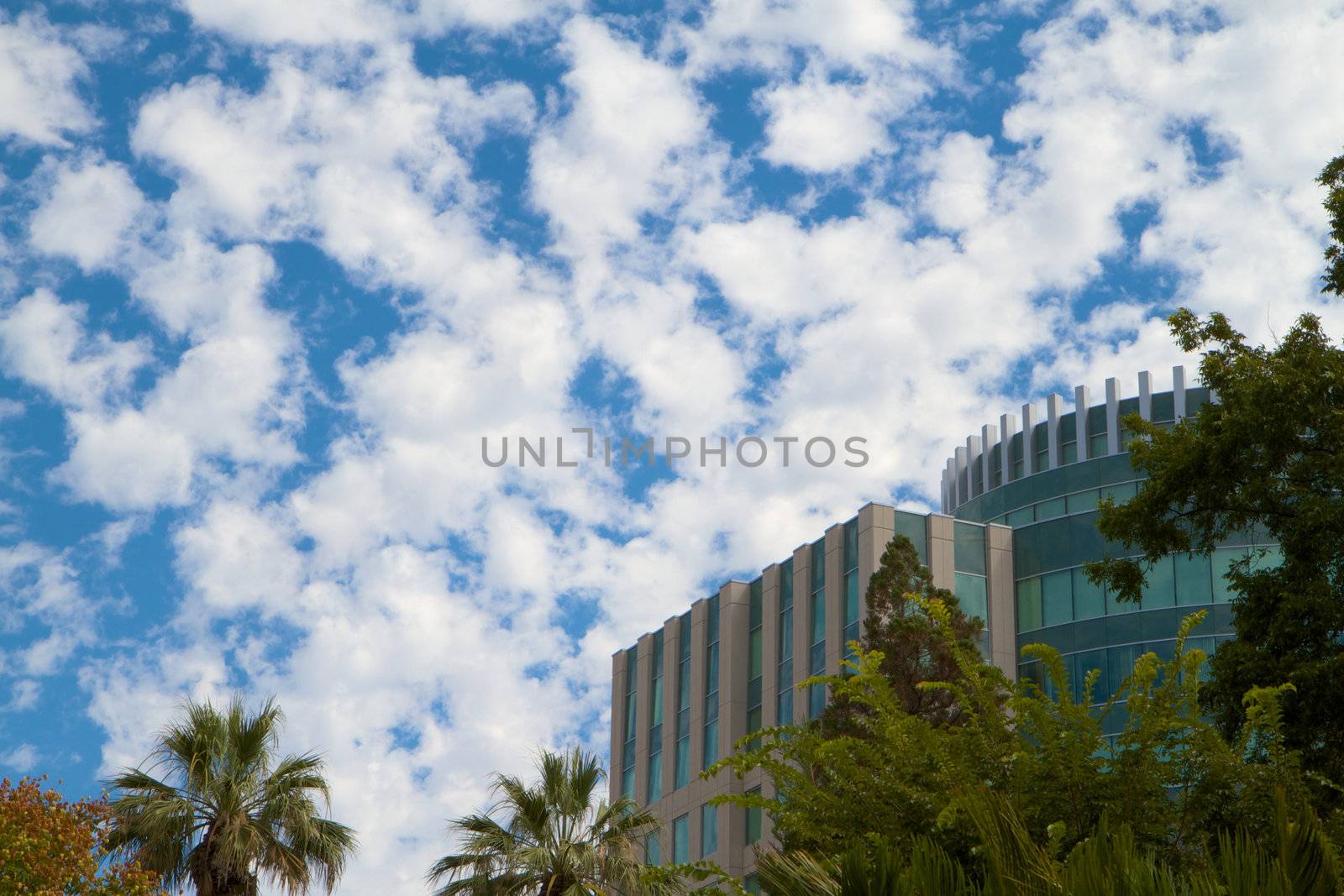Blue green teal buildings against bright blue sky with puffy clouds