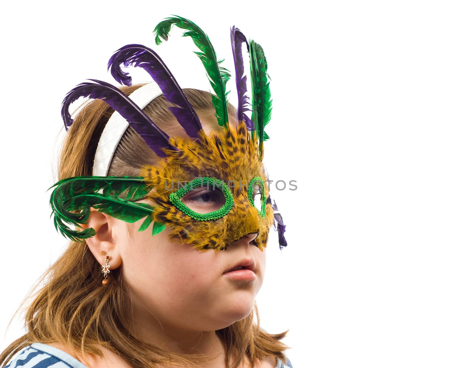 Closeup of a young girl wearing a masquerade mask, isolated against a white background