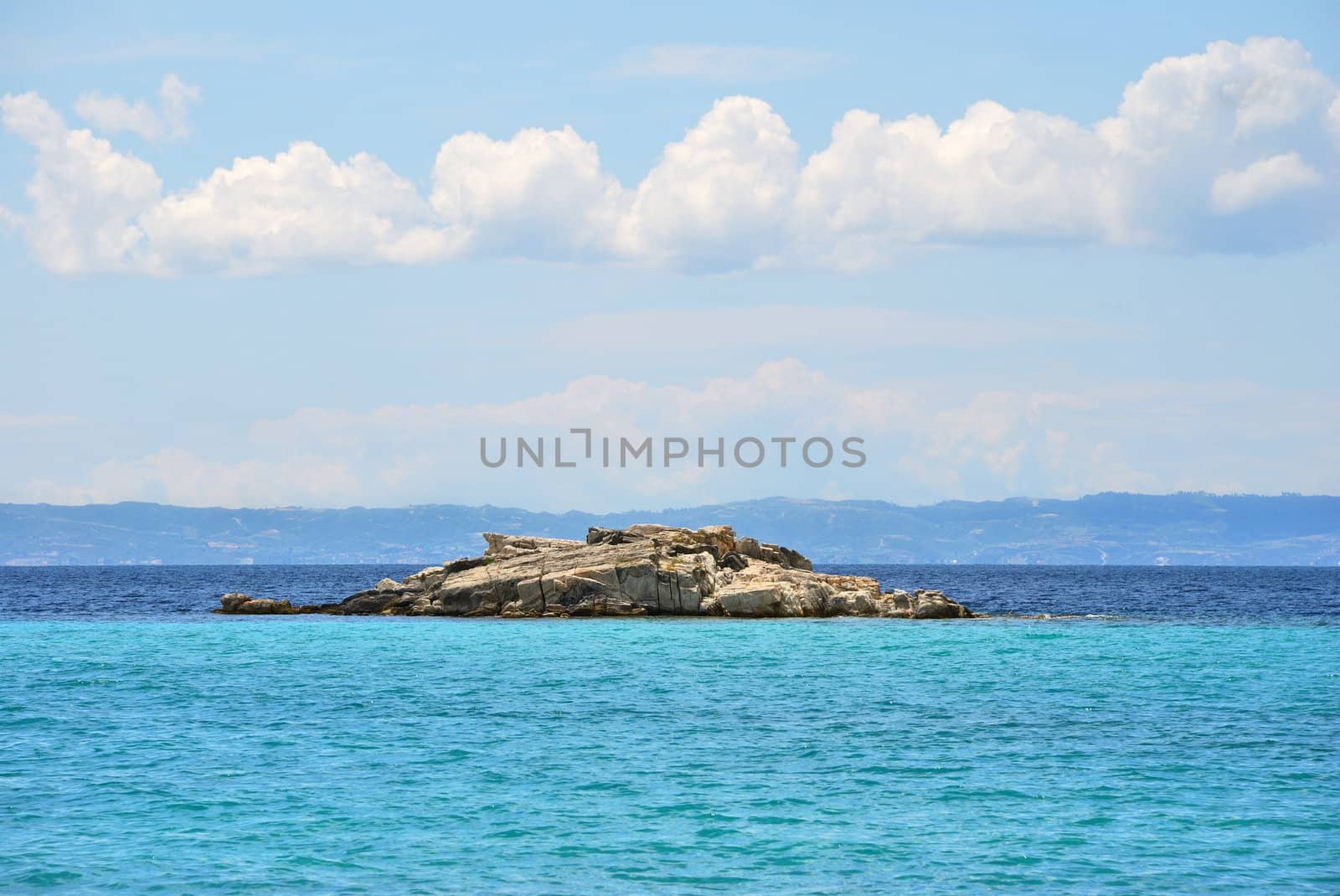 Small rocky island near Kalogria beach in Sithonia, Chalkidiki, Greece, with a view on Kassandra peninsula.