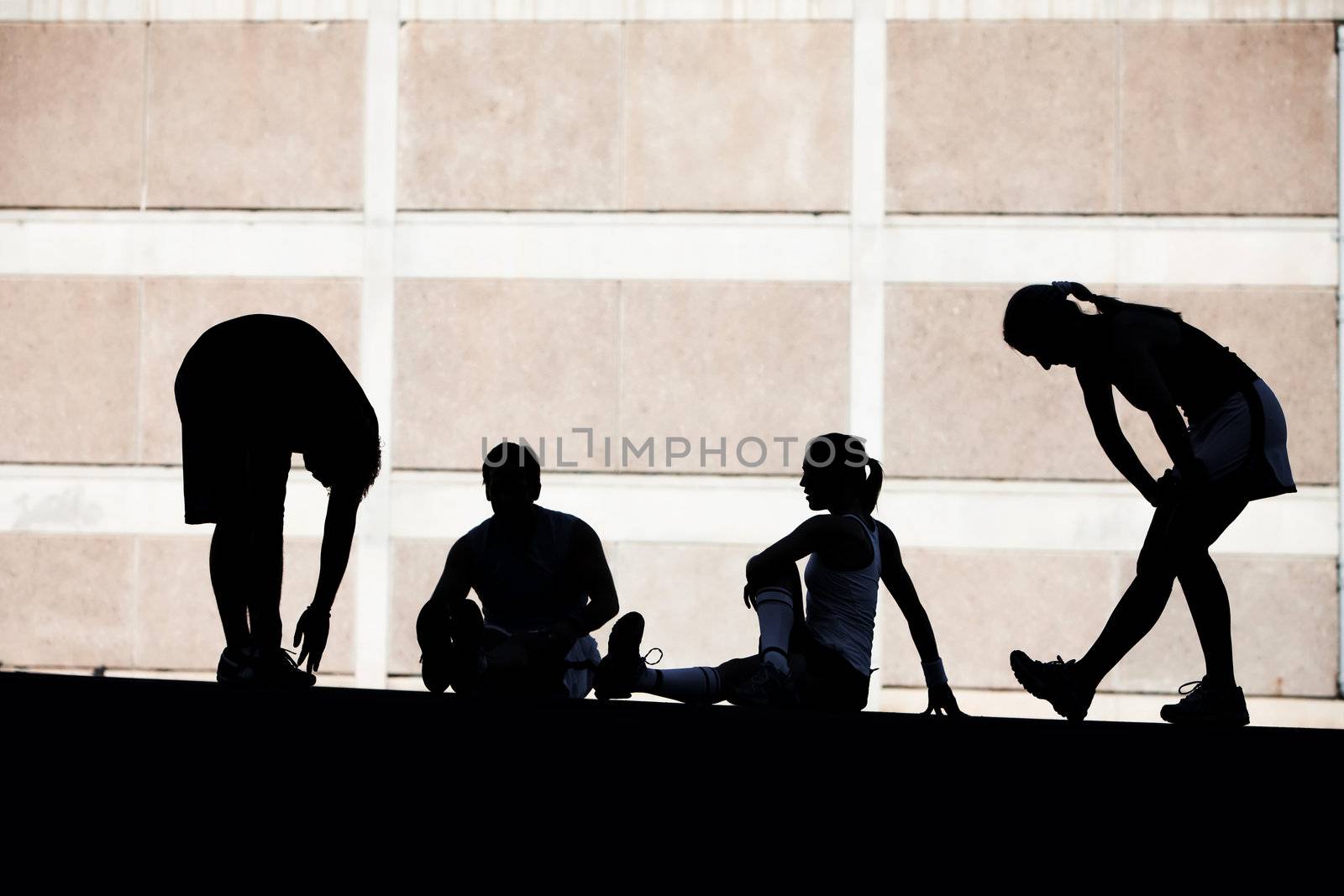 Men and women runners stretching. by Creatista