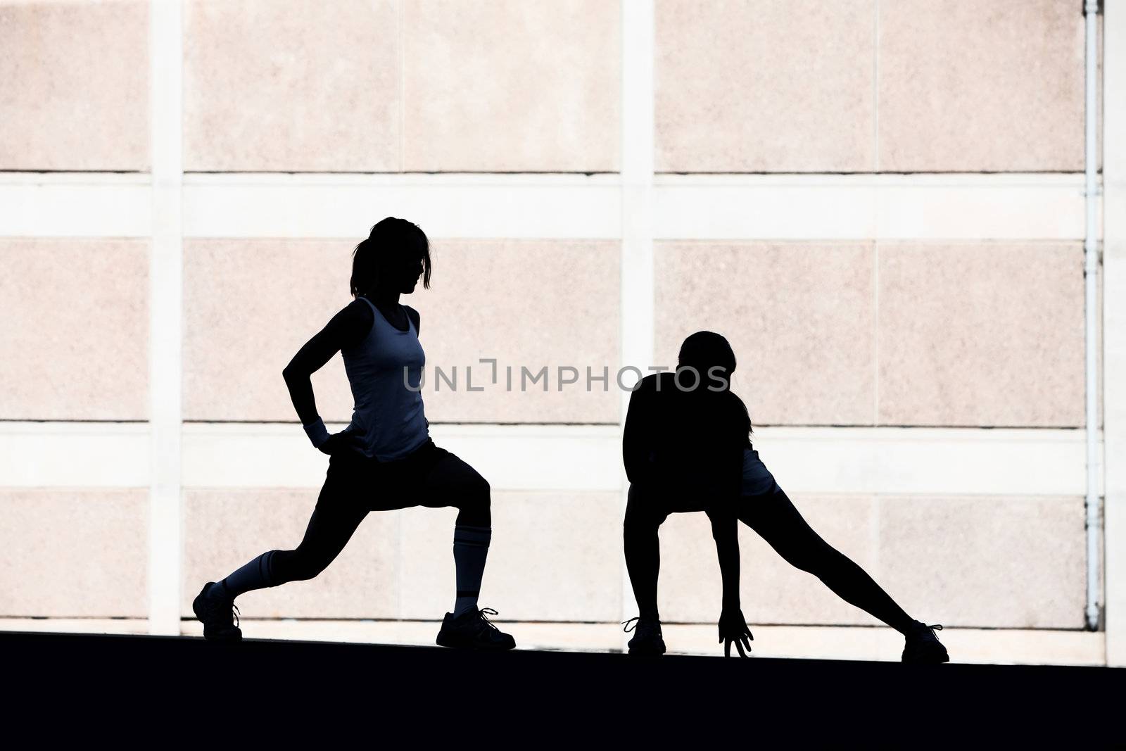 Two female friends stretching before a run.