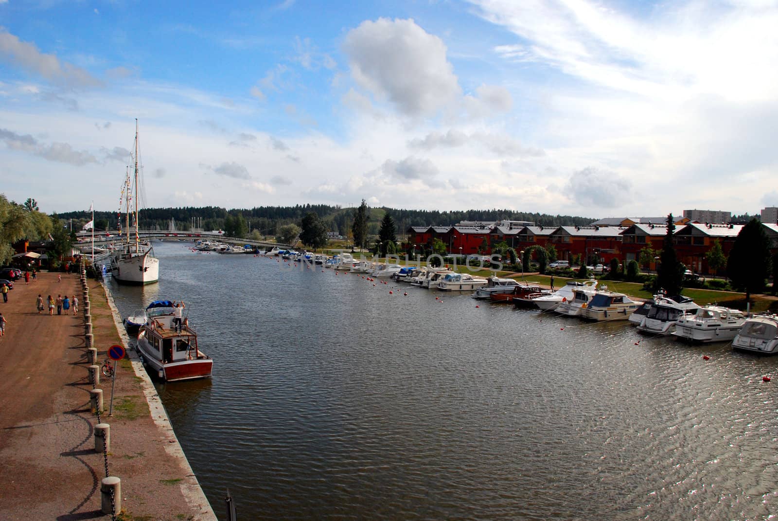 A view of Porvo from a bridge, with the river and many boats. in the background we can see houses and the blue and cloudy sky.