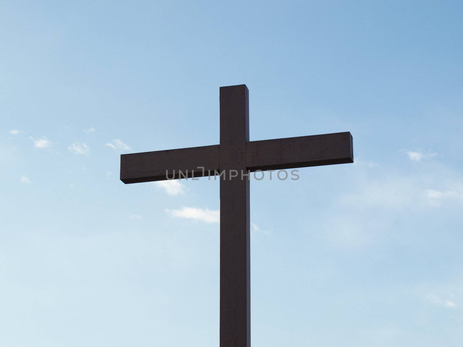 Wooden cross over a blue sky with clouds