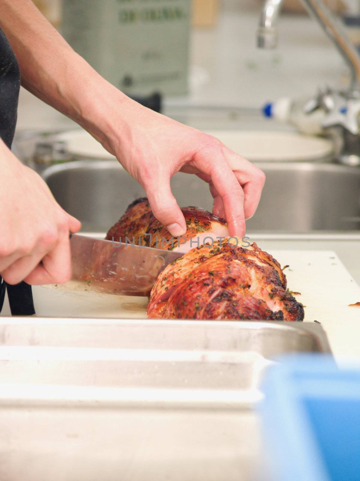 Chef cutting roast ham in a  kitchen