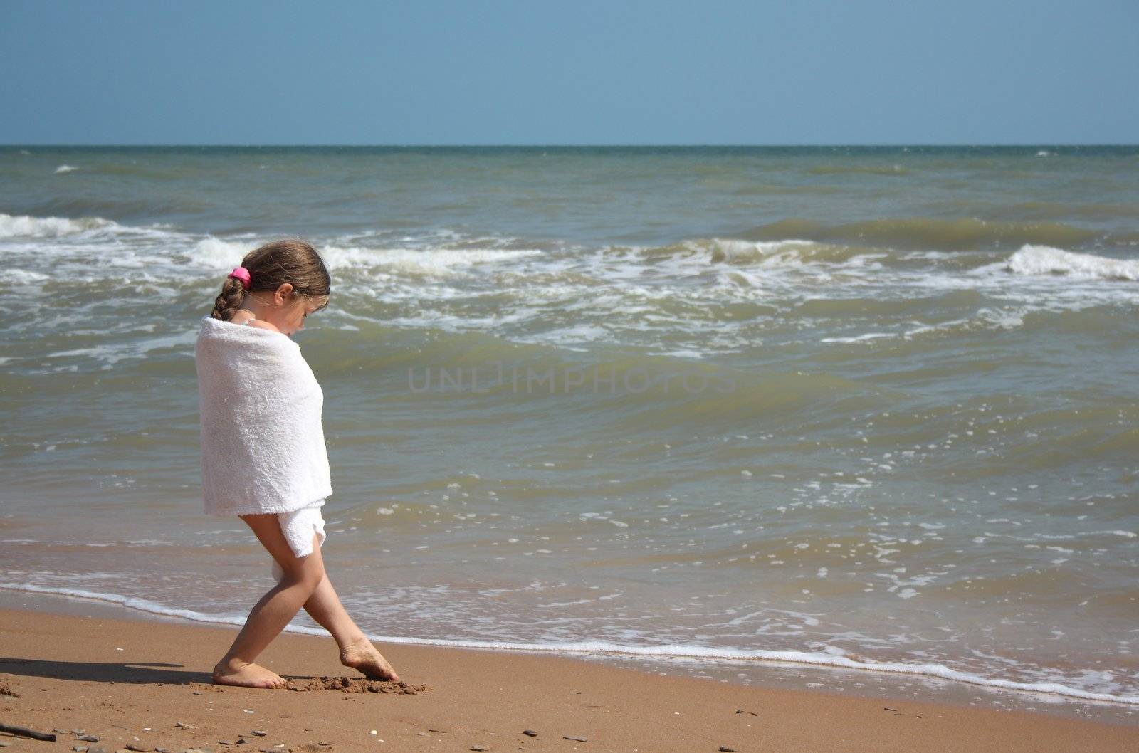 Little girl on seacoast in white towel by yippikaye