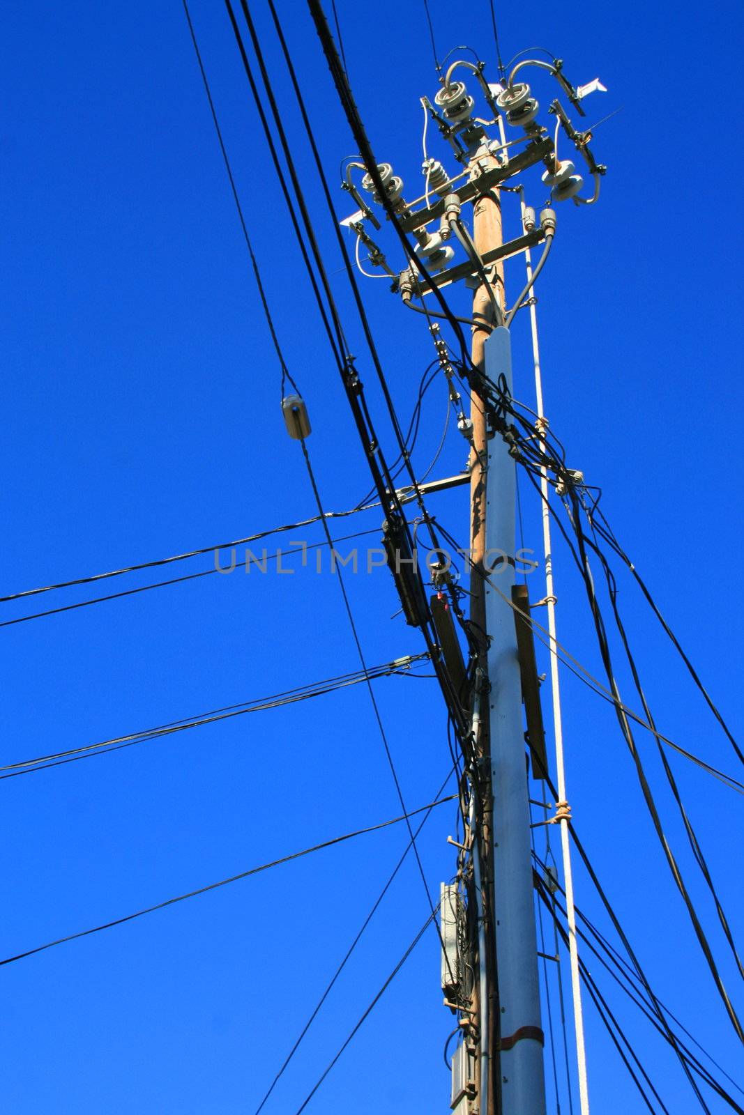 Close up of an electricity pole over blue sky.