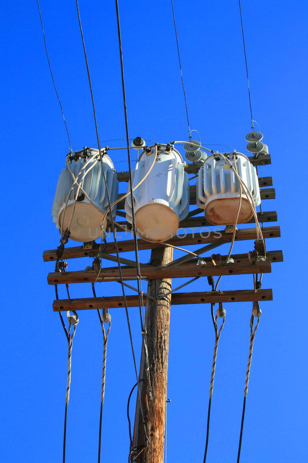 Close up of an electricity transformer over blue sky.
